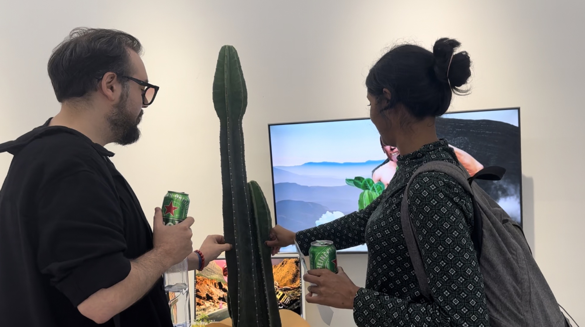 Two visitors gently touching the cactus while the collage animation plays on a nearby screen